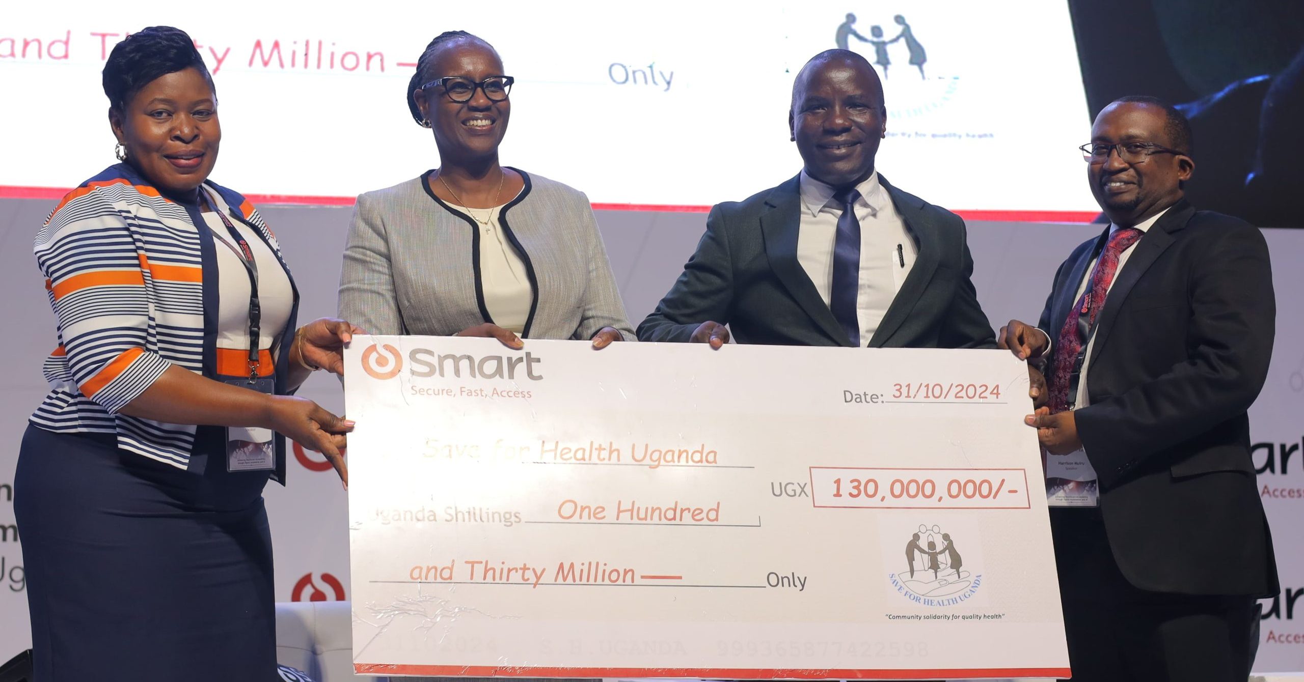 Smart Applications team (Marry Ann Musangi- Board Director (2nd Left, Mr. Harrison Muiru-Group Managing Director (Extreme Right) and Ms. Judy Mugoya- Country Manager-Uganda (Extreme Left) handing over a cheque to Mr. Fredrick Makaire- SHU Executive Director (2nd right)